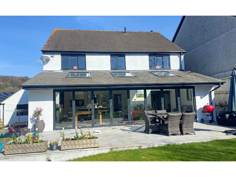 Single-storey rear extension with full-width aluminium bifold doors and skylights, opening onto a paved patio.